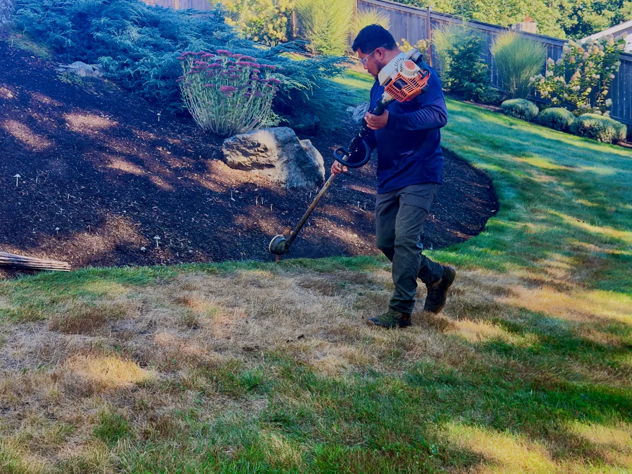 A crew member works the cleared bank above the lawn
