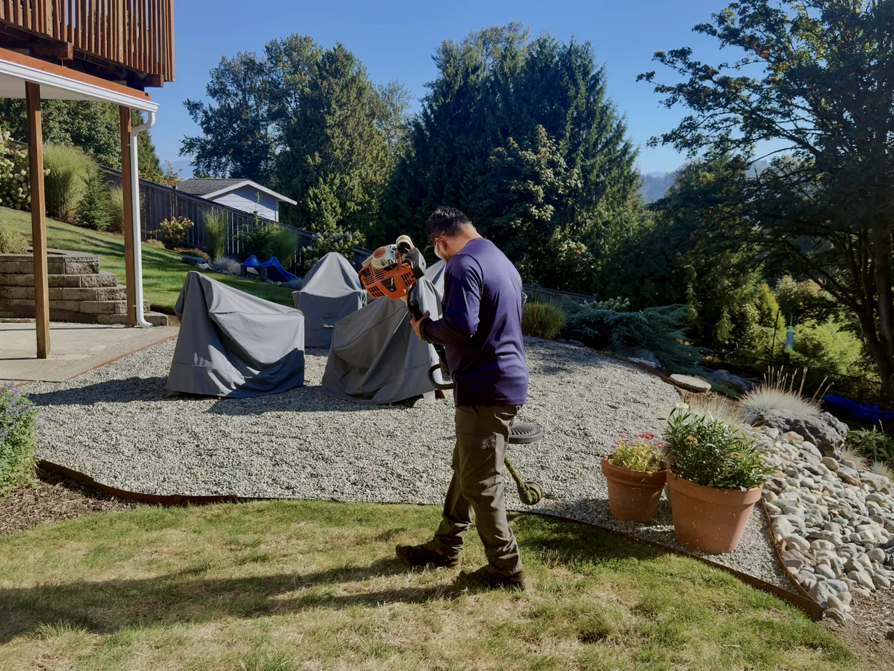 Crew member trimming a bed edge on a gravel terrace