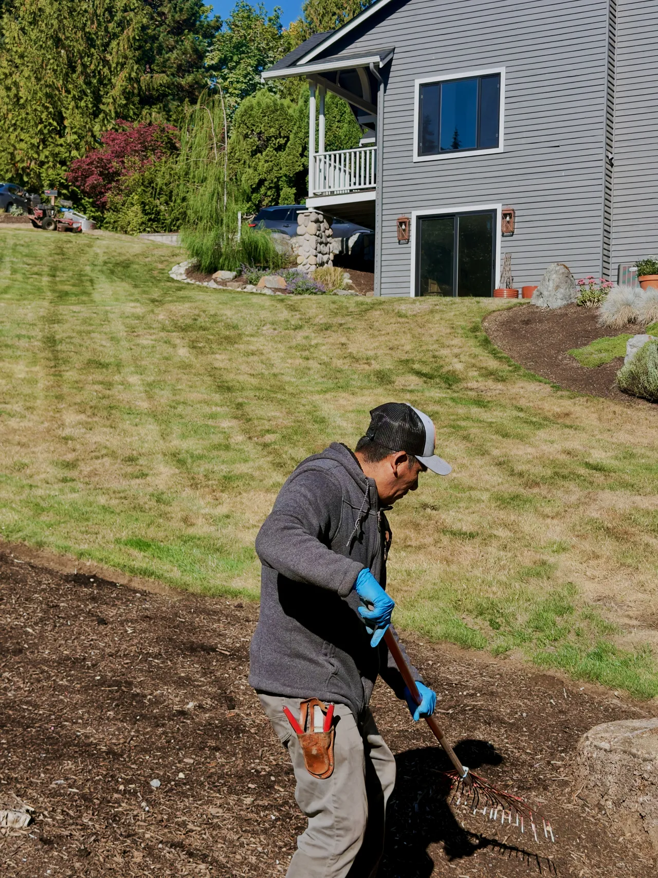 A crew member rakes a new bed beside the lawn
