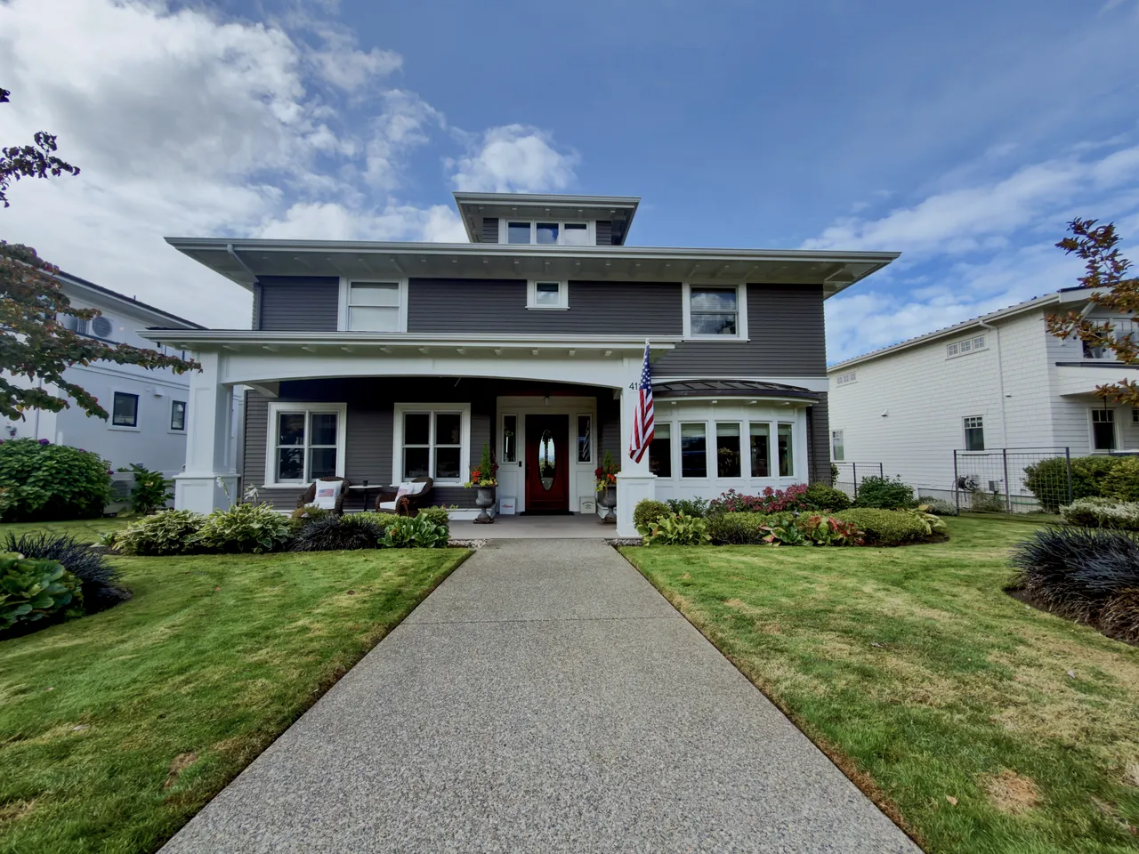 Grey foursquare house with a lawn and a concrete drive